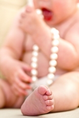 Infant holding pearls